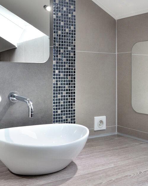 Suite parentale sous les combles avec mise en valeur des poutres. Création de rangements sous les rampants. Magnifique salle de douche épurée et raffinée. L'ensemble de l'espace est ouvert pour une très belle perspective. Les tons de dégradés de gris, bleu, chrome, sont réchauffés par le bois et les briques rouges.