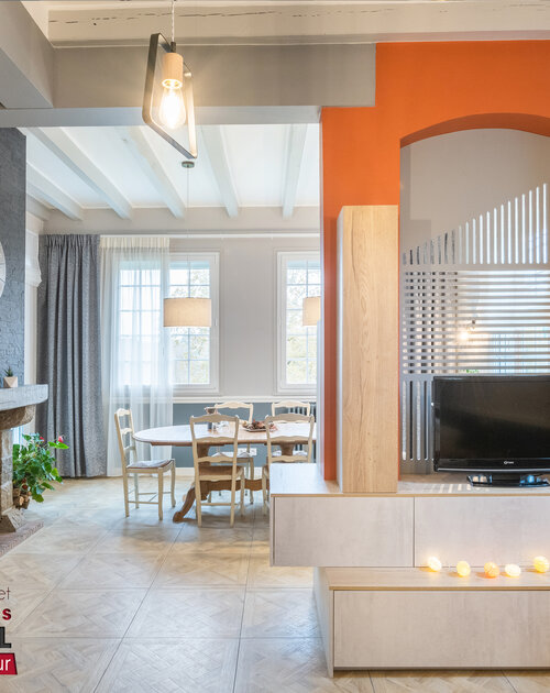 Très belle rénovation de la pièce de vie d'une maison au bord du lac. Les couleurs chaudes valorisent les dégradés de bleus et gris. Les agencements apportent des rangements fonctionnels et optimisent la pièce. Sol, murs, rideaux, mobiliers, luminaires, tous les éléments ont été recherchés pour une belle harmonie cohérente