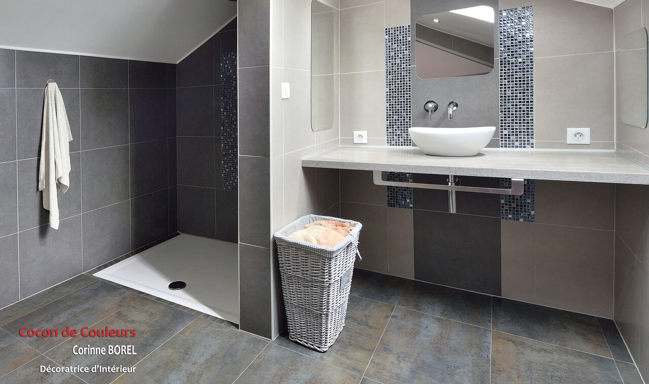 Suite parentale sous les combles avec mise en valeur des poutres. Création de rangements sous les rampants. Magnifique salle de douche épurée et raffinée. L'ensemble de l'espace est ouvert pour une très belle perspective. Les tons de dégradés de gris, bleu, chrome, sont réchauffés par le bois et les briques rouges.